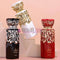 Tres frascos de perfume Diwani en negro, blanco y rojo, con elegantes detalles árabes, sobre fondo rosa.