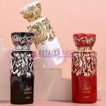 Tres frascos de perfume Diwani en negro, blanco y rojo, con elegantes detalles árabes, sobre fondo rosa.