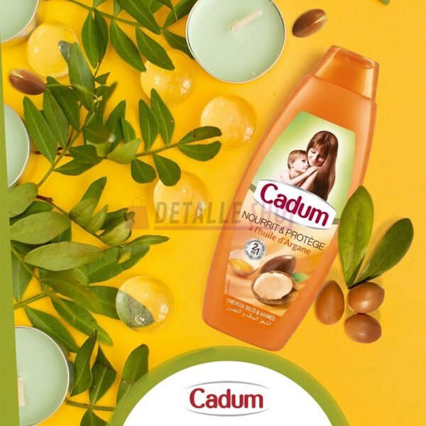 Champú Cadum de aceite de argán rodeado de hojas verdes, nueces de argán y velas en un fondo amarillo